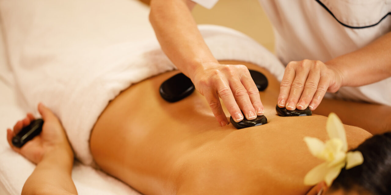 Unrecognizable woman receiving hot stone therapy at the spa.