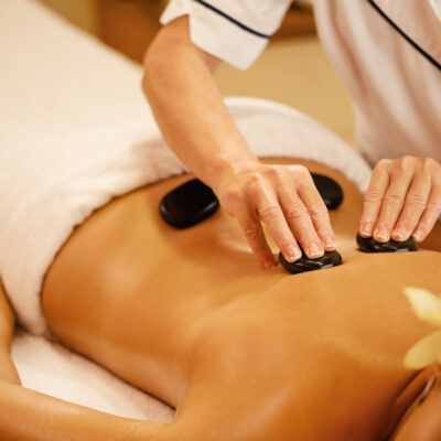 Unrecognizable woman receiving hot stone therapy at the spa.